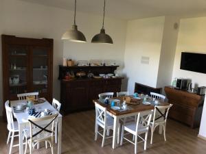 B&B Quattro Stagioni في Gli Angeli: غرفة طعام مع طاولتين وكراسي بيضاء