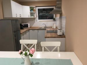 a kitchen with white cabinets and a table with pink flowers at Tisza Dream Apartman in Tiszakécske