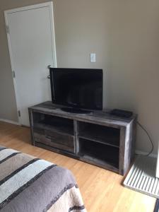 a flat screen tv on a wooden stand in a room at Kacee's Northern Suites in Fort Nelson