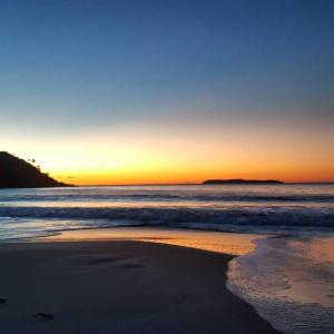 una puesta de sol en la playa con el océano en Morada d'Omar 4 Ilhas, en Bombinhas