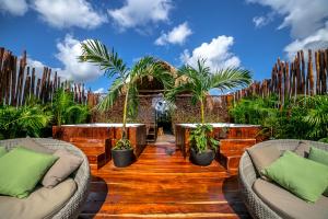 a patio with two tables and chairs and palm trees at Grand Balam Plaza in Tulum