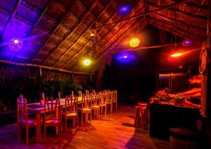 Grand Balam Plaza في تولوم: غرفة طعام مع طاولات وكراسي وأضواء أرجوانية