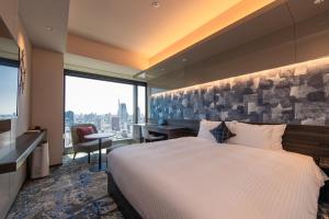 a hotel room with a bed and a desk and a window at THE BLOSSOM HIBIYA in Tokyo