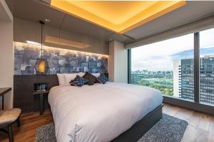 a bedroom with a large bed and a large window at THE BLOSSOM HIBIYA in Tokyo