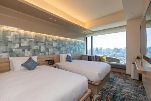 two beds in a hotel room with a large window at THE BLOSSOM HIBIYA in Tokyo