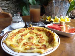 uma pizza num prato numa mesa com uma bebida em Puri Asri Bungalow Ubud em Ubud