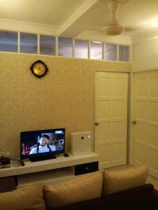 sala de estar con sofá y TV en la pared en Fastbook Bendera Home 8 & 10pax, en Ayer Itam