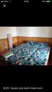 un letto con un piumone verde e fiori sopra di Hillside Village apartment 72sqm size with kitchen a Siquijor