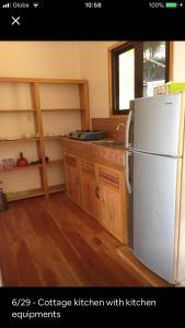 La cuisine est équipée d'un réfrigérateur blanc et de placards en bois. dans l'établissement Hillside Village apartment 72sqm size with kitchen, à Siquijor