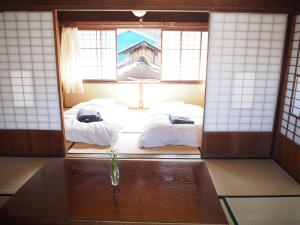 Dos camas en una habitación con mesa y ventanas. en NORA, en Numazu