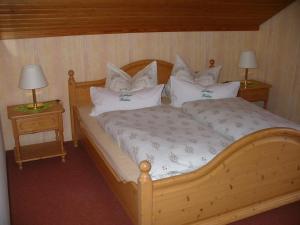 a bedroom with a wooden bed with white pillows at Landhaus Kathrin in Walkenried