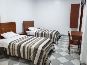 a hotel room with two beds and a chair at Shale Hotel in Chachapoyas
