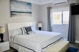 a white bedroom with a bed and a window at The Marina Villa de Sonja in Ocho Rios