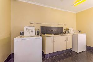 a kitchen with a microwave, refrigerator, sink, and dishwasher at Quality Hotel Darwin Airport in Darwin