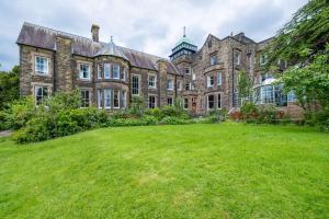 un vieux bâtiment avec une grande cour devant lui dans l'établissement Makeney Hall Hotel, à Derby