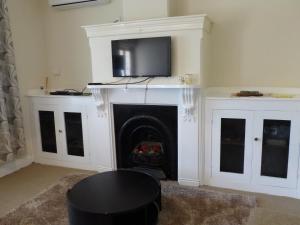 a living room with a fireplace with a tv above it at Andy's Accommodation in Peterborough