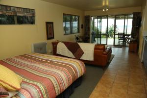 a bedroom with a bed and a balcony at Gems Seaside Lodge in Ahipara