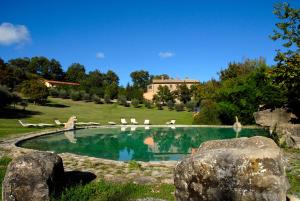 a swimming pool with chairs and a house in the background at Agriturismo Paradiso41 in Assisi