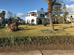 una casa con una palmera delante de ella en Villa Eden Park sur la plage, en Fnidek