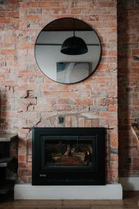 a brick wall with a mirror and a fireplace at Apartments on Belmore -The Ferguson in Yarrawonga