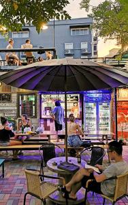 a group of people sitting at tables under an umbrella at Here Hostel Bangkok in Bangkok