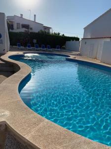 una piscina azul con sillas en un patio en Apartamentos Xoroi en Cala'n Porter