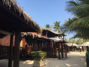 a building with thatched roofs and palm trees at Nilaveli Beach Resort - Level 1 Certified in Nilaveli