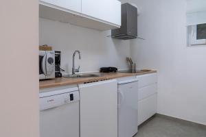 托爾明的住宿－The FOXhouse，白色的厨房配有白色橱柜和水槽