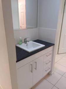 La salle de bains est pourvue d'un lavabo blanc et d'un miroir. dans l'établissement Waratah and Wattle Apartments, à Maryborough