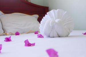 two white birds sitting on a bed with purple flowers at Quoc Dinh Guesthouse in Mui Ne
