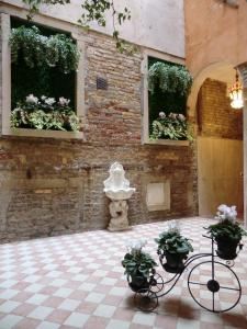 ein Zimmer mit zwei Fenstern mit Pflanzen und einer Statue in der Unterkunft Locanda Cà Le Vele in Venedig