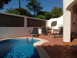 uma piscina num pátio com cadeiras e uma cerca em Villa Oleander no Vale do Lobo