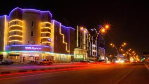 eine Stadtstraße in der Nacht mit Gebäuden und Straßenbeleuchtung in der Unterkunft Rona Al Khobar Hotel in Khobar