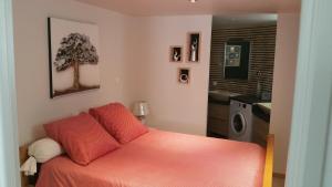 a bedroom with a bed with orange sheets and a bathroom at Les 3 marguerites in Luzenac