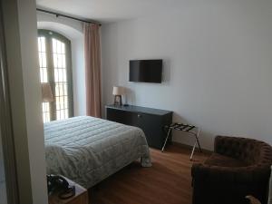 a bedroom with a bed and a chair and a television at Jardi de Pedra in L'Escala