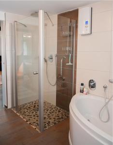uma casa de banho com um chuveiro e uma banheira branca em Ferienwohnung Sonnentau 2 em Holzminden