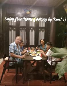 een groep mensen die rond een tafel zitten te eten bij An Bang Stilt House Villa in Hội An