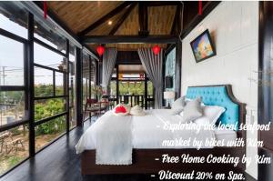 een slaapkamer met een bed in een kamer met ramen bij An Bang Stilt House Villa in Hội An