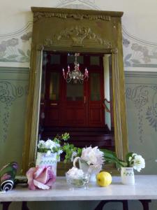 un miroir assis au-dessus d'une table avec des fleurs dans l'établissement Apartment Hermine, à Görlitz