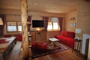 a living room with a red couch and a tv at Jörgnerhaus in Kals am Großglockner