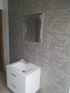 a bathroom with a white sink and a brick wall at Noclegi nad Parsętą in Białogard