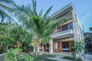 een huis met palmbomen ervoor bij Jero Griya Ubud in Ubud