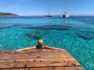 Eine Frau, die auf einem Steg im Wasser liegt. in der Unterkunft VisitAylinVis in Vis