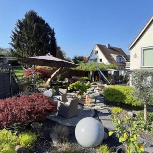 un jardín con sombrilla, sillas y plantas en Haus Steffi en Müllheim