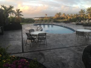 um pátio com mesas e cadeiras ao lado de uma piscina em Mauna Kai'iki em Pahala