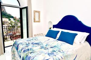 a bedroom with a large bed with a blue headboard at Gema Suites in Positano