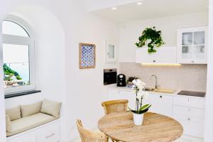 a white kitchen with a wooden table and chairs at Gema Suites in Positano