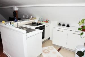 - une cuisine blanche avec évier et cuisinière dans l'établissement Apartment Grcic, à Sarajevo