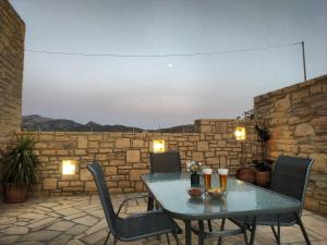 a table and chairs on a patio with a stone wall at Angela in Triopetra