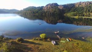 Laguna Larga Lodge في Lago Futalaufquen: اطلالة جوية على بحيرة مع قوارب على الشاطئ